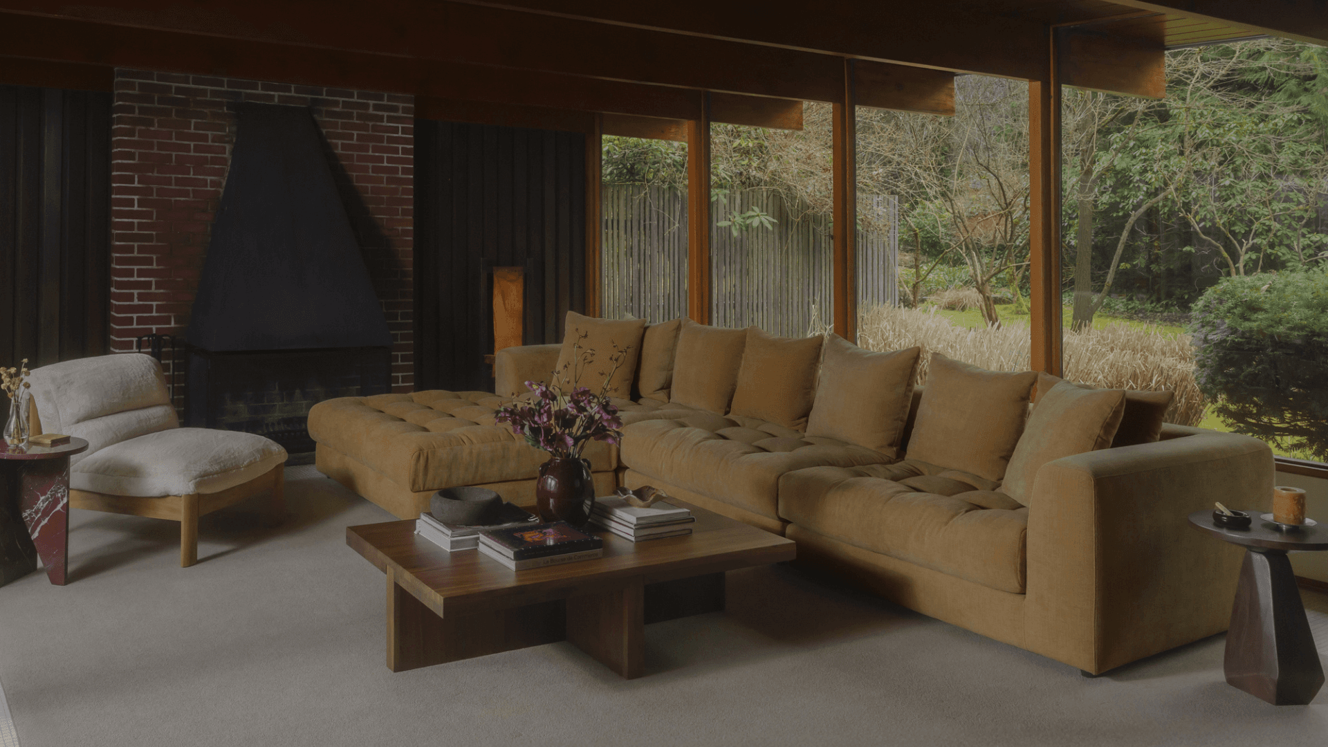 A warm mid-century living room with a Kömfi sectional by a brick fireplace